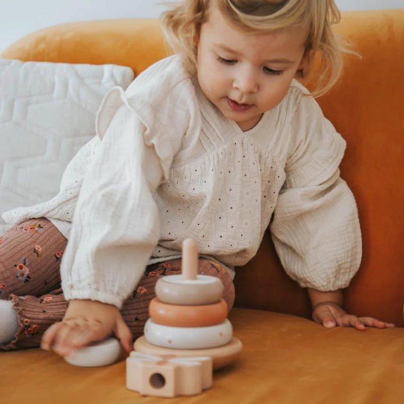 Kind spielt mit personalisiertem Balance Stapelturm aus Holz in Nougat von Label Label als Geschenk zur Taufe mit Name und Taufdatum