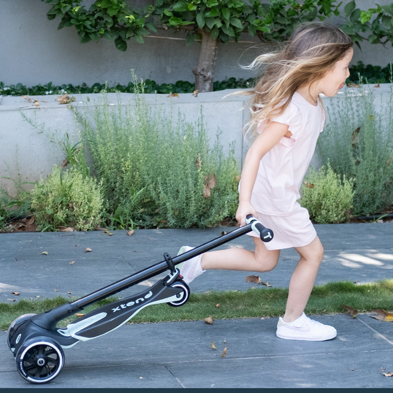 Kind zieht zusammenklappbaren Kinder Scooter hinter sich beim Gehen im Alltag