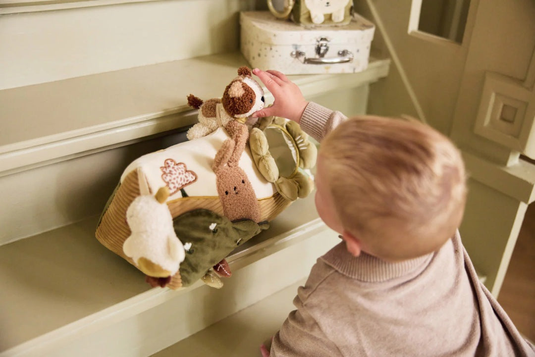 Baby spielt mit einem Aktivitätsdreieck mit Spiegel und sensorischen Spielelementen zur Förderung der frühkindlichen Entwicklung