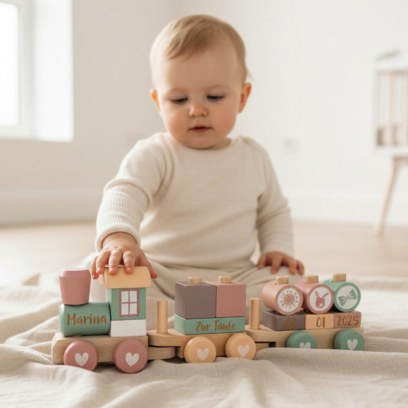 Baby mit personalisiertem Holzzug in Rosa als Geschenk zur Taufe – individuell mit Name und Taufdatum gestaltet